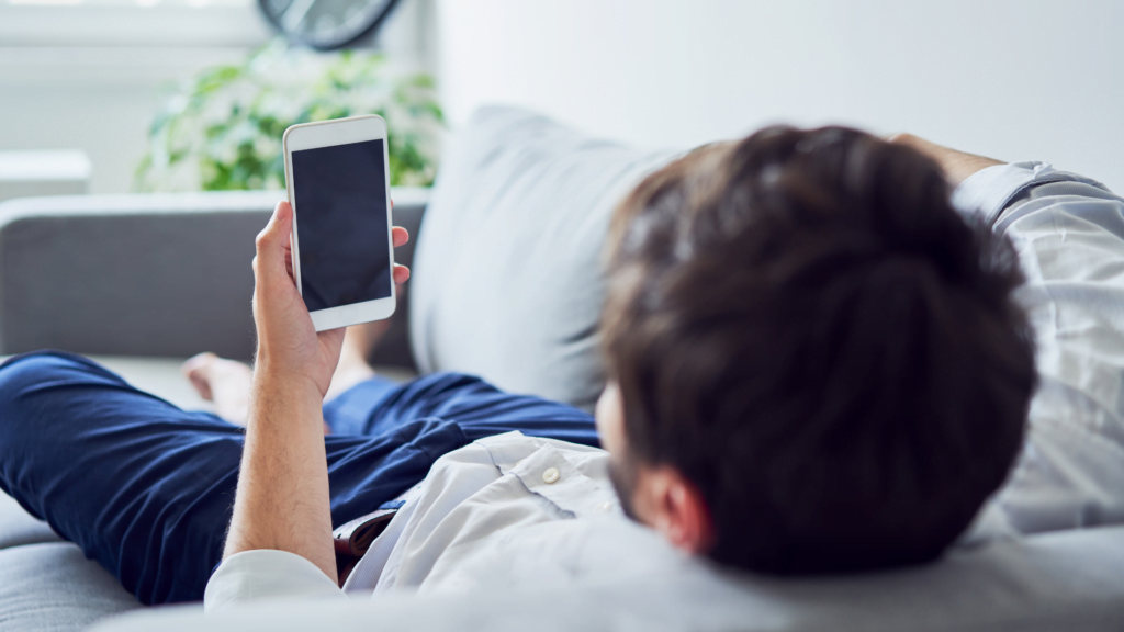 Man lying on the sofa with mobile phone