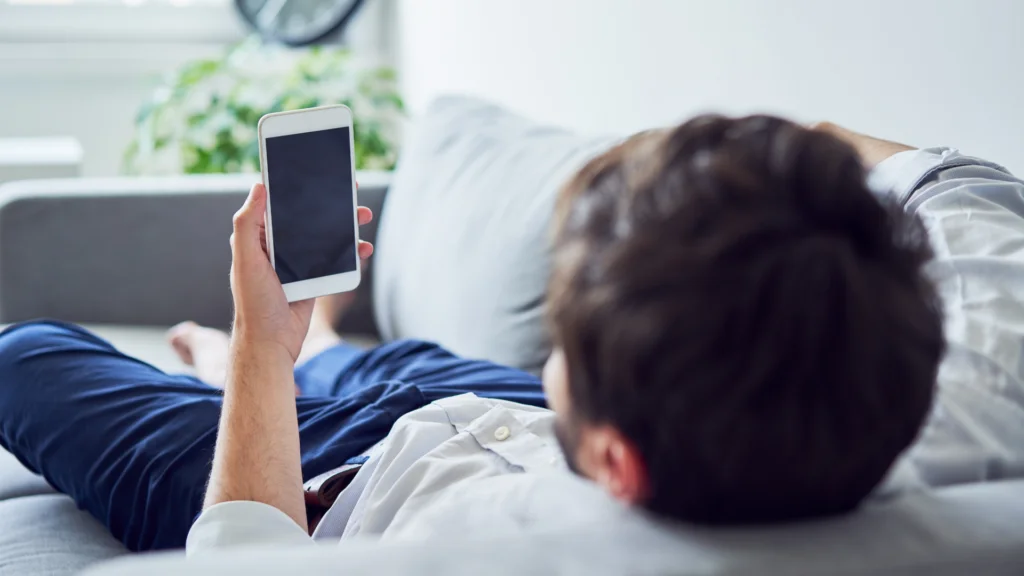 Man lying on the sofa with mobile phone
